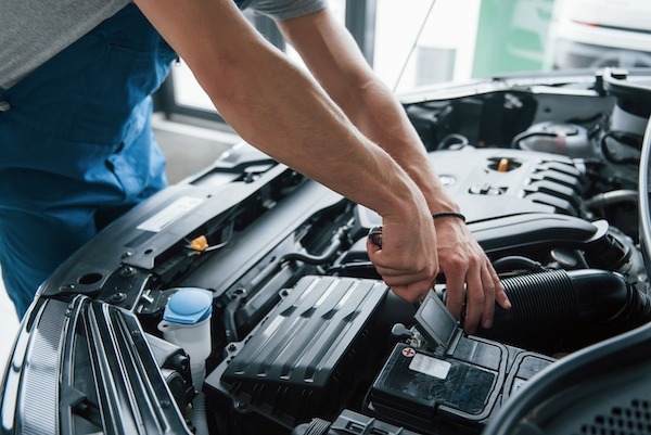 Some electronic parts. Process of repairing car after accident. Man working with engine under the hood.